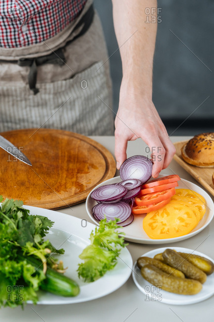 Man cutting veggies for burgers