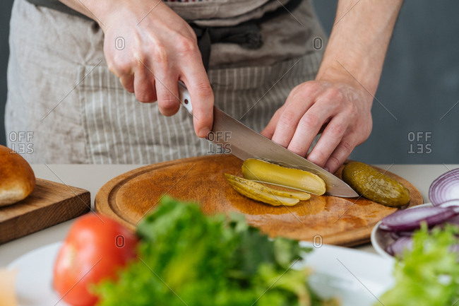 Chef cutting pickles for burgers
