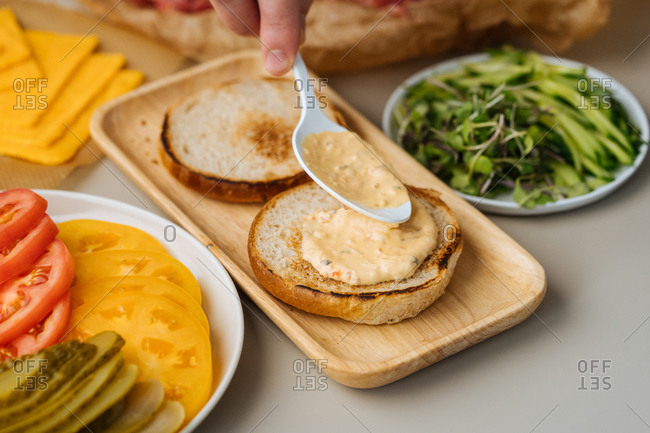 Chef putting sauce on burger bun