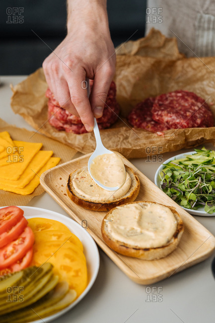 Chef spreading sauce on burger bun