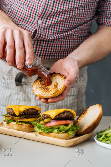 Chef adding ketchup to a cheeseburger