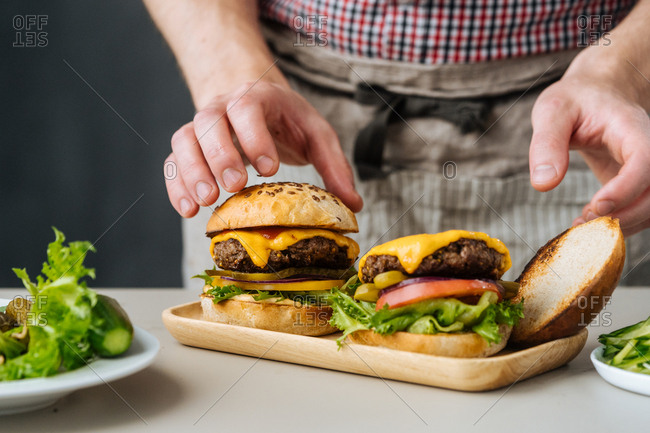 Chef adding top bun to a cheeseburger