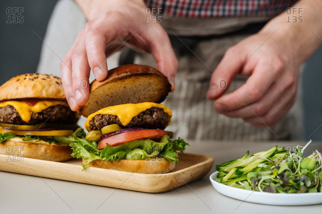 Chef placing top bun on a cheeseburger