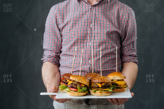 Man holding a variety of cheeseburgers