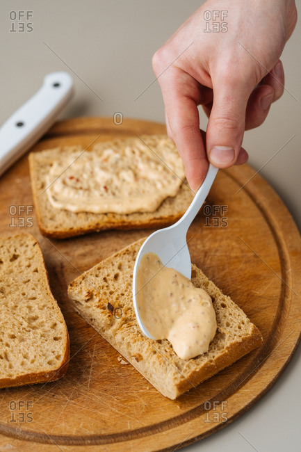 Man spreading sauce onto bread for sandwich