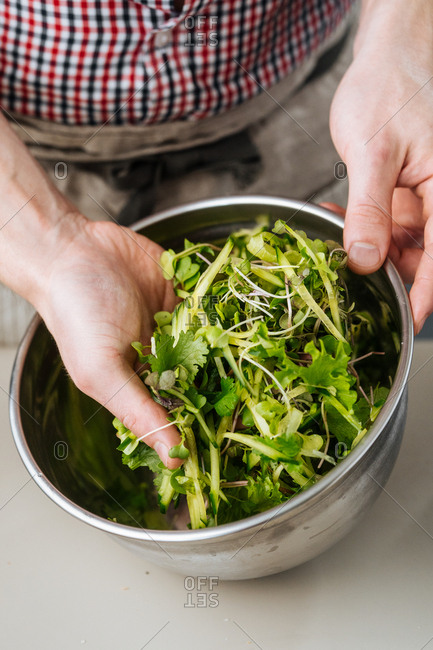 Chef mixing herbs and vegetables in a bowl