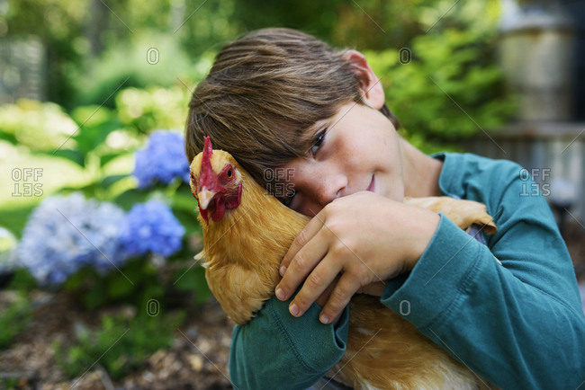 Young boy cuddling a chicken