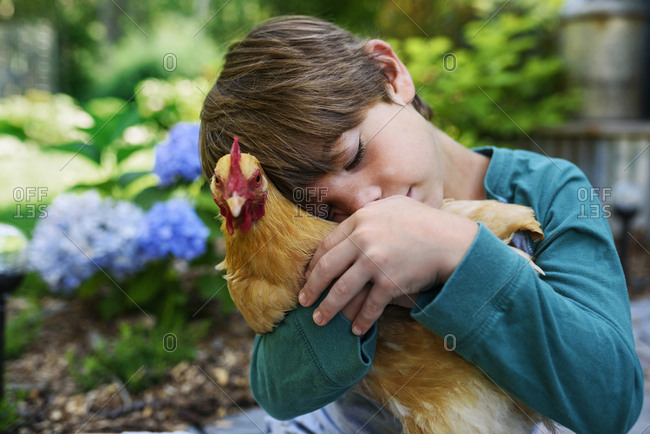 Young boy cuddling a chicken