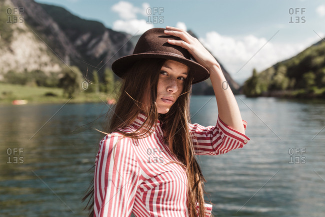 Portrait of young vintage woman looking at camera in a sunny day lake and mountains background