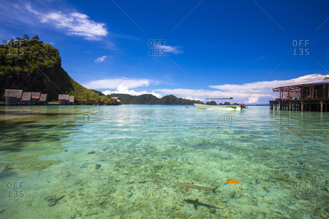 Scenic view of sea with rowboat and huts on coastline, Misool, Raja Ampat, Indonesia