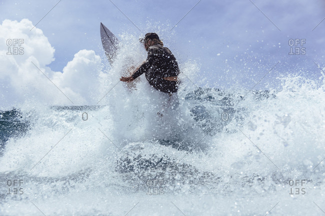 Male surfer splashing while riding wave against sky, Male, Maldives