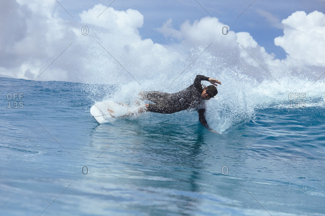 Male surfer slanting while riding wave against clouds, Male, Maldives