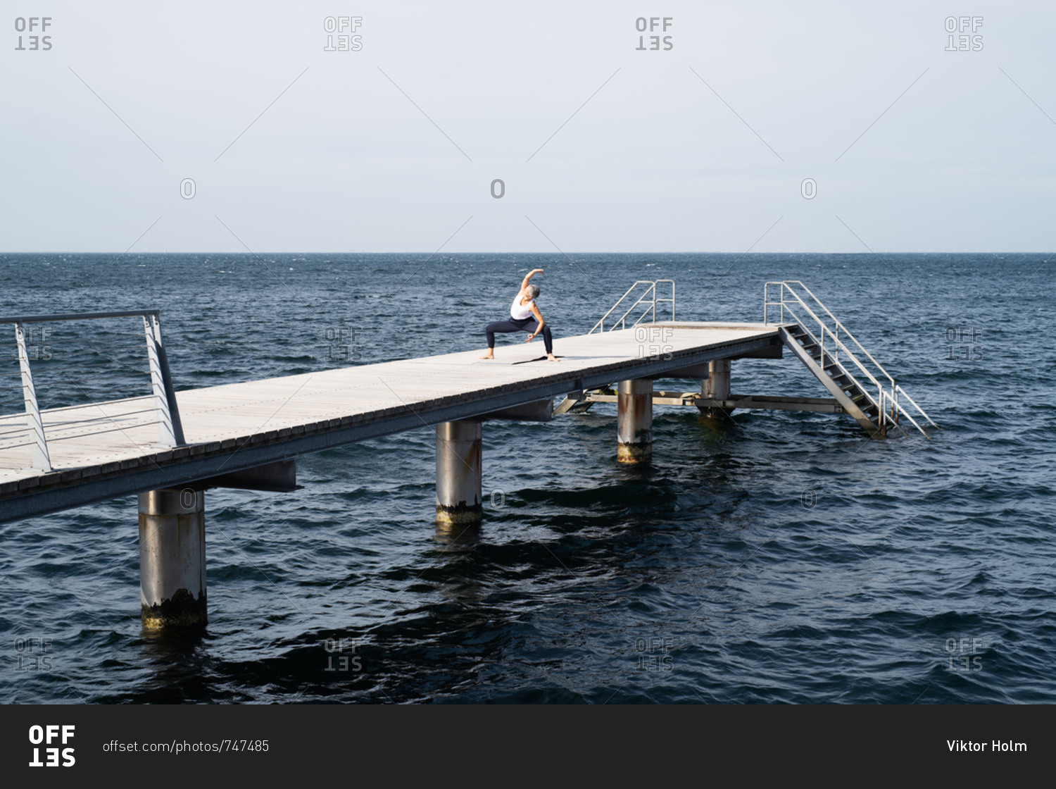 Middle-aged woman stretching during workout on ocean pier