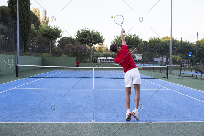 Man hitting ball with power while playing tennis on court