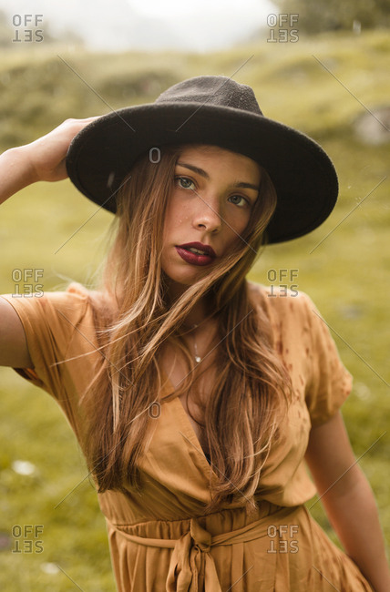 Portrait blonde woman of blue eyes and black hat looking away from camera
