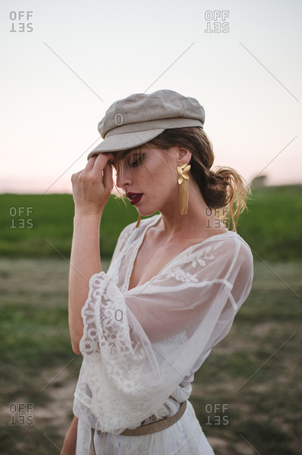 Blonde woman with beret and white dress posing and relaxing in a meadow