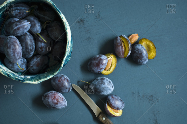 Sliced and whole plums and a kitchen knife