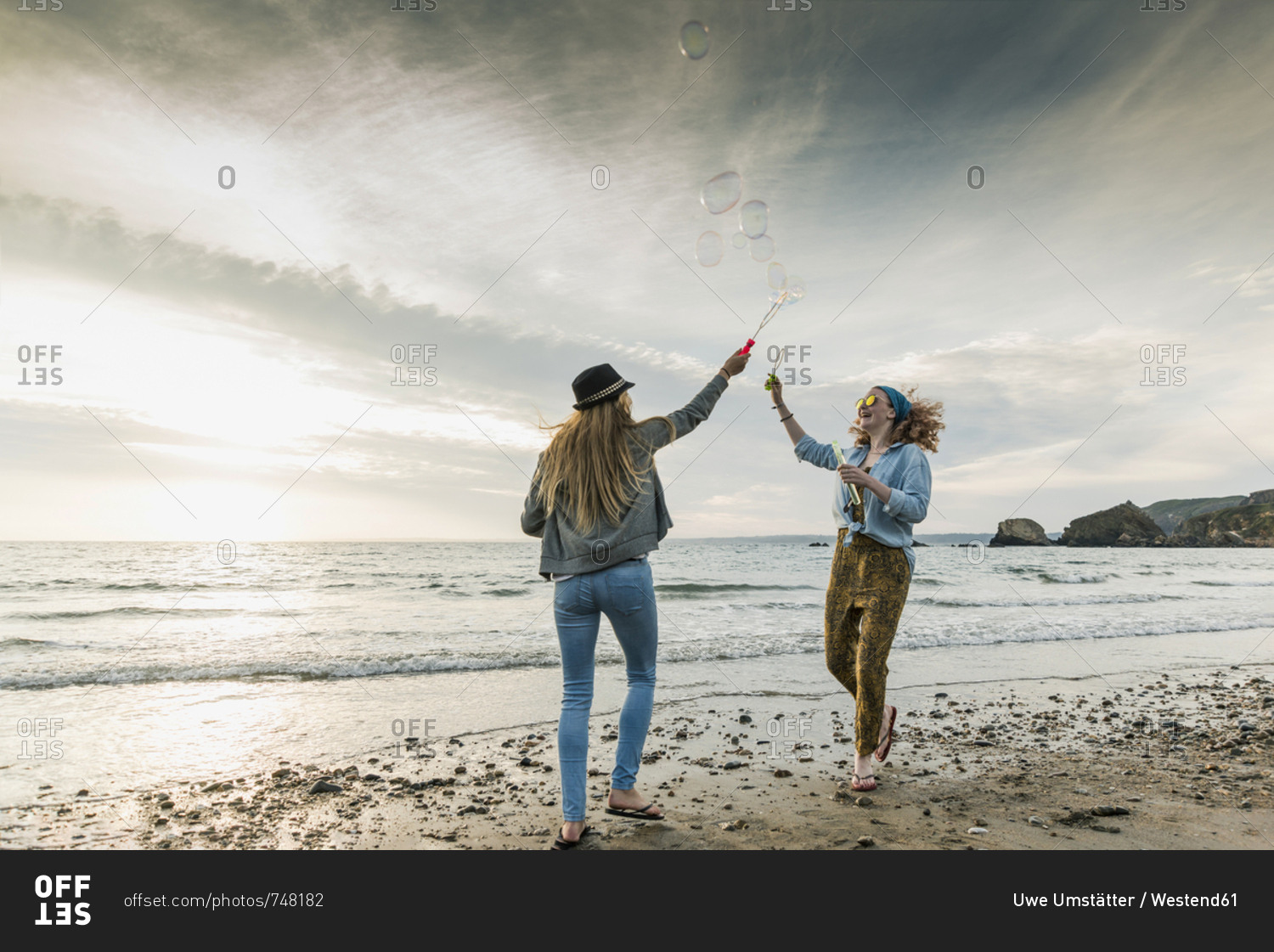 Happy friends making soap bubbles on the  beach
