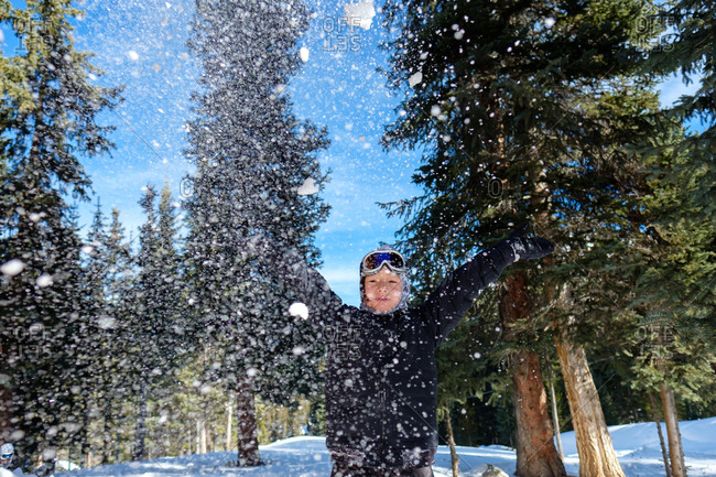 Boy with outstretched arms throwing snow outdoors