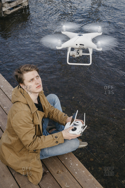 A handsome young man is holding a remote from the drone. flying drone on the background of water. close-up