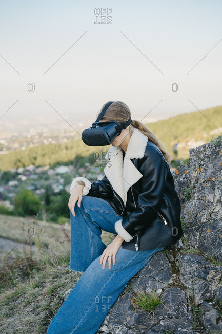 Portrait of a beautiful young woman wearing virtual reality glasses while outside in the forest