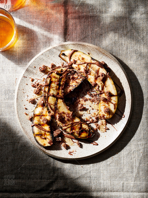 A plate of grilled bananas with chocolate peanut butter and crumbled cookies