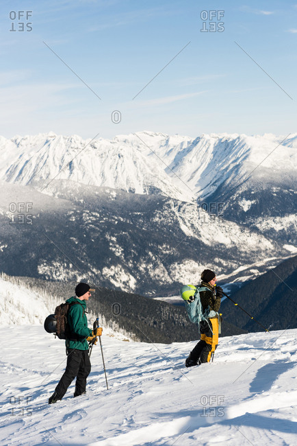Male and female skiers walking on a snowy mountain during winter