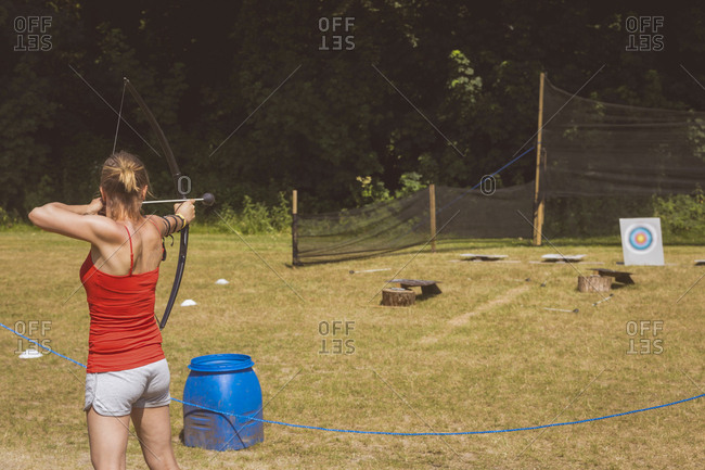 Woman practicing archery at boot camp on a sunny day