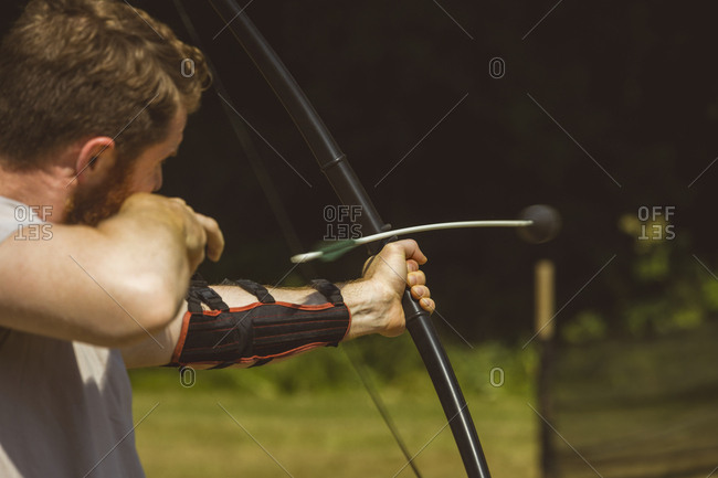 Man practicing archery at boot camp on a sunny day
