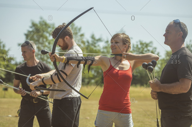 Trainer instructing woman about archery at boot camp