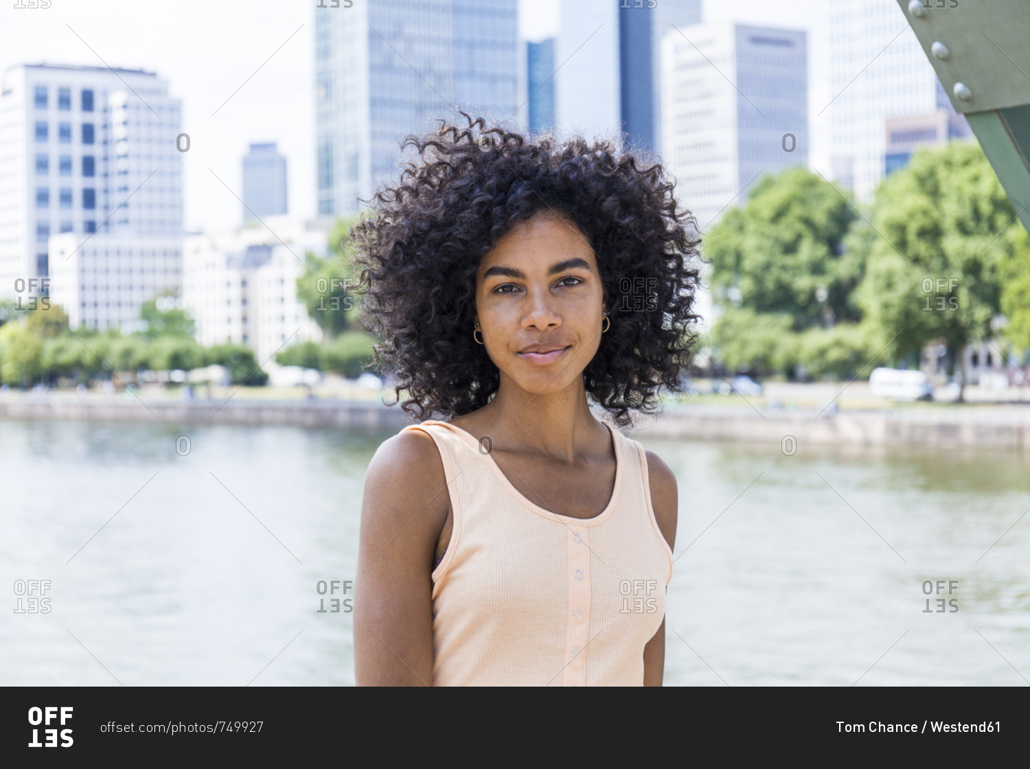 Germany, Frankfurt, portrait of relaxed young woman with curly hair in front of Main River