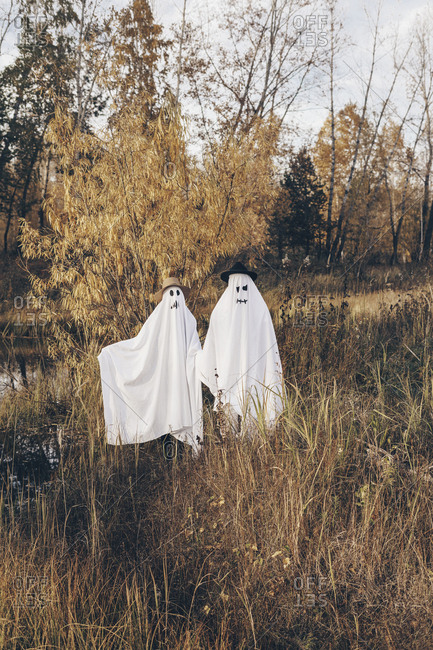 Two people dressed up as ghosts standing in a field