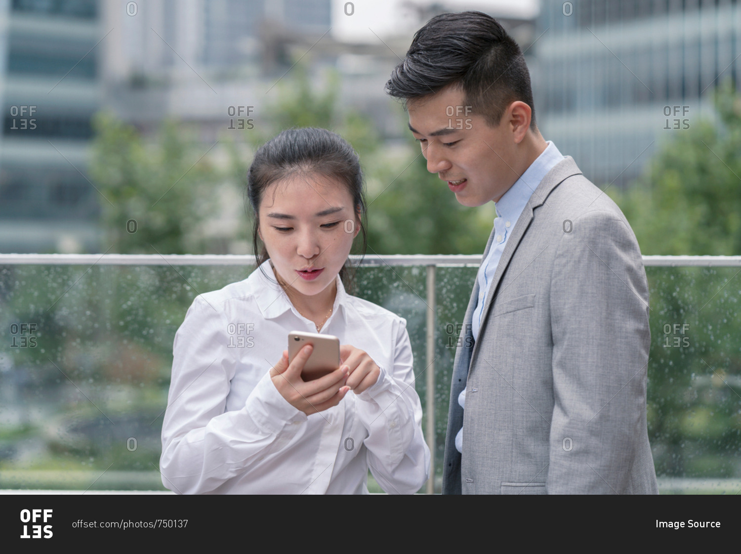 Young businesswoman and man looking at smartphone in city, Shanghai, China