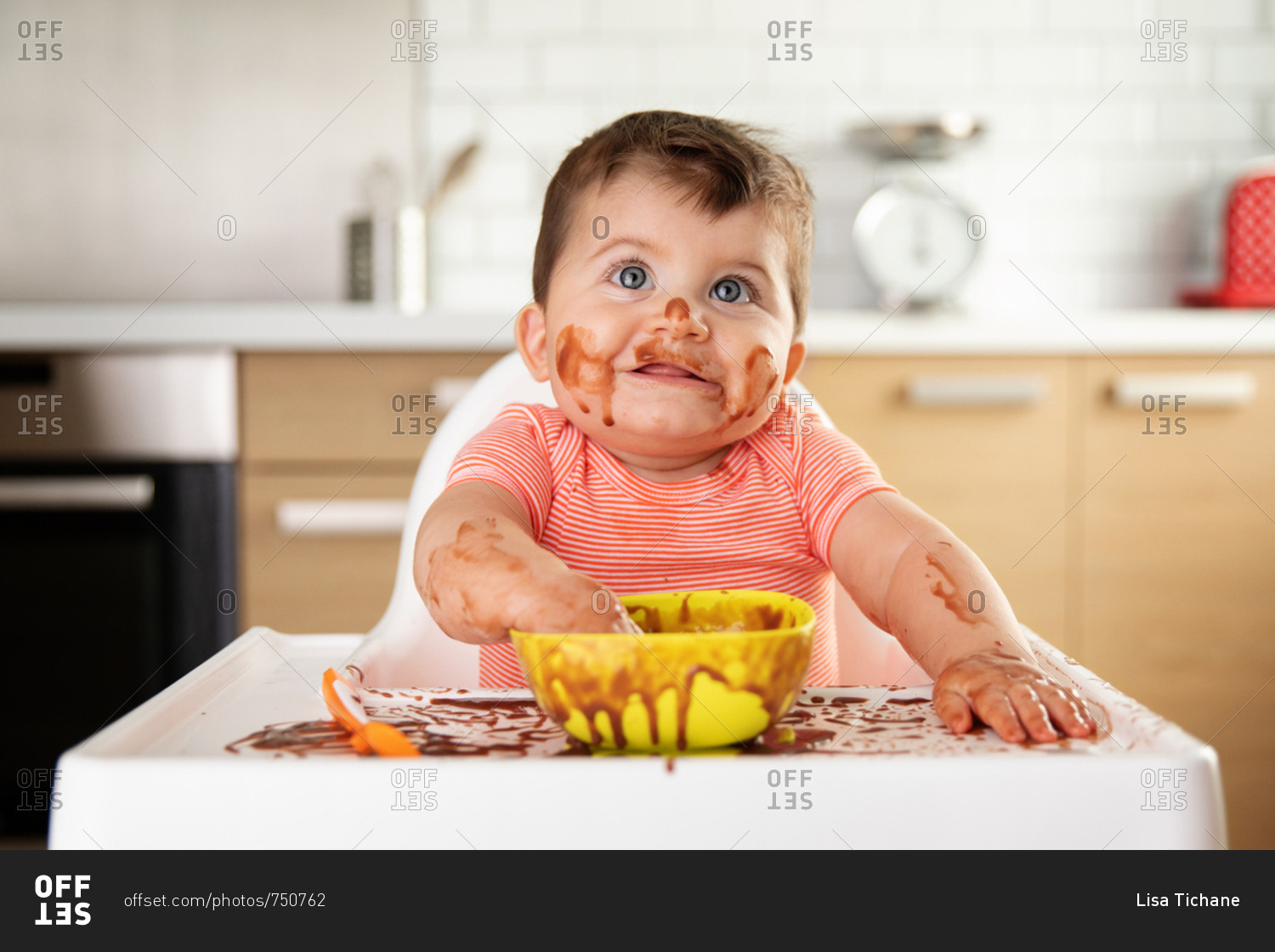 Baby making mess while eating pudding in high chair
