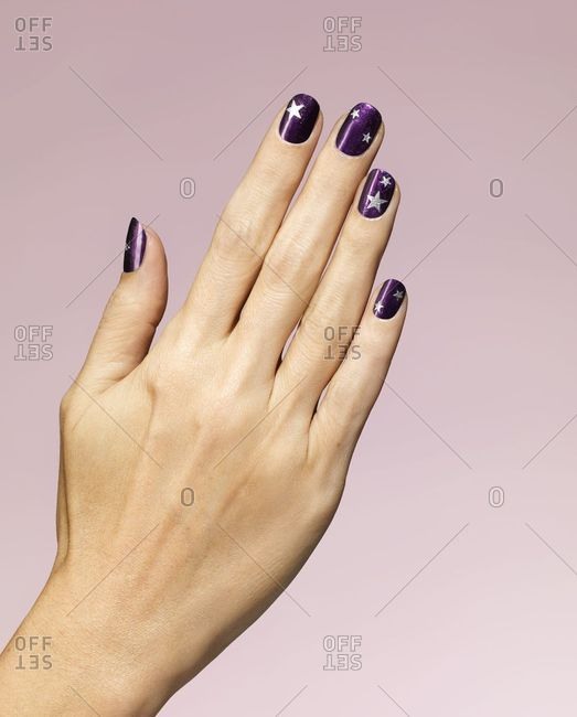 Woman\'s hand with purple star nail polish