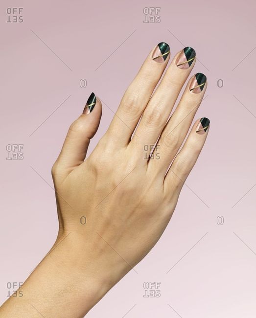 Woman\'s hand with green and gold nail polish