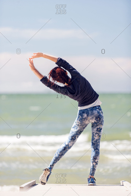 Woman stretching by the ocean during workout