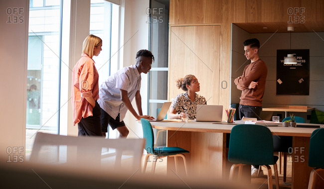 Female creative business colleagues having an informal meeting in a large  office, full length view