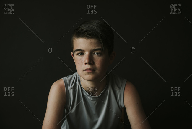 Portrait of confident boy sitting against black background