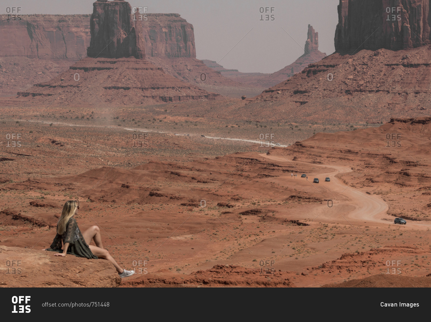 Side view of female hiker looking at buttes while sitting on rocks in Monument Valley Tribal Park during sunny day