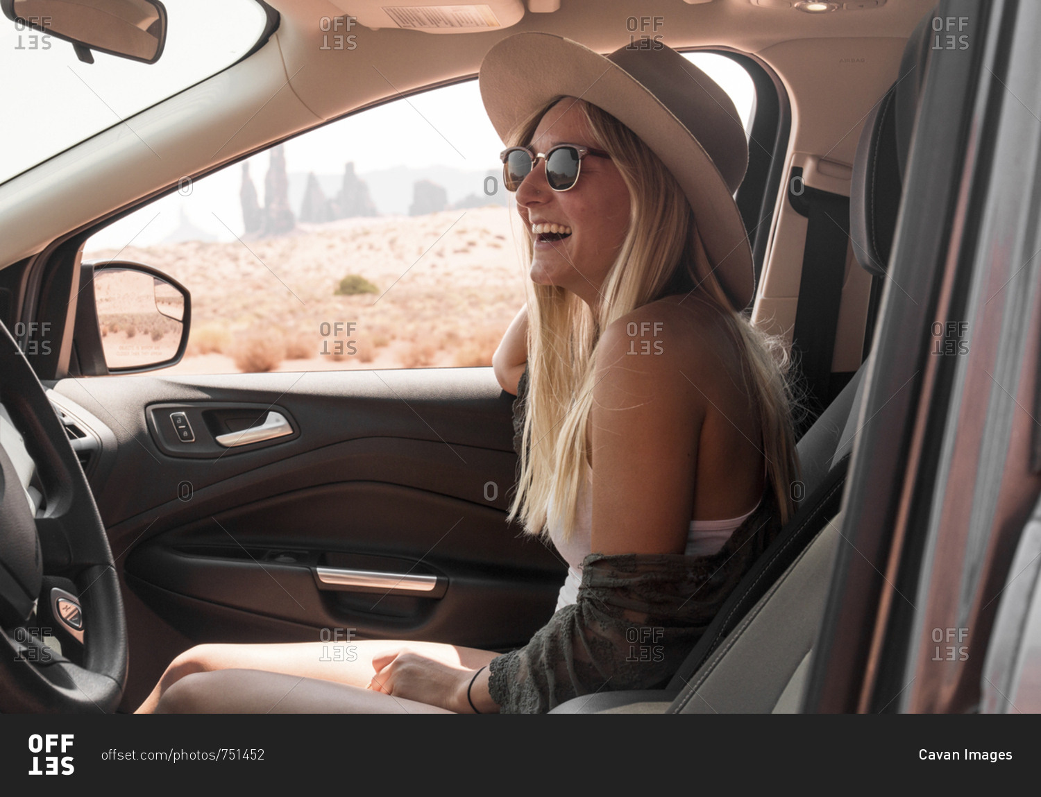Side view of happy woman wearing hat and sunglasses while traveling in car at Monument Valley Tribal Park