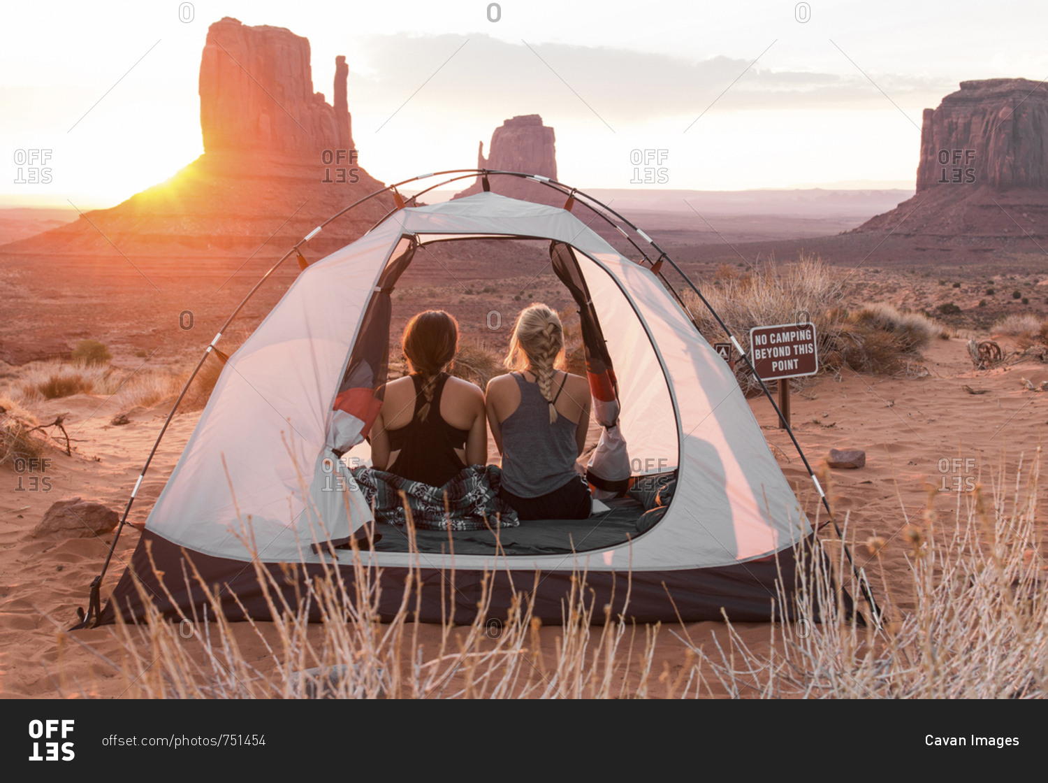 Rear view of friends sitting in tent against sky at Monument Valley Tribal Park during sunset