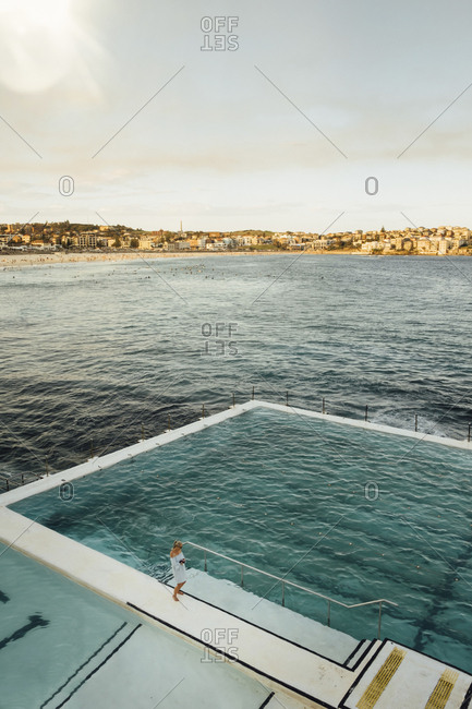 Australia, Sydney - August 25, 2018: Aerial view of woman standing by infinity pool at Bondi Beach against sky