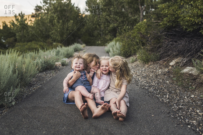 Happy cute sisters sitting on road against trees in forest