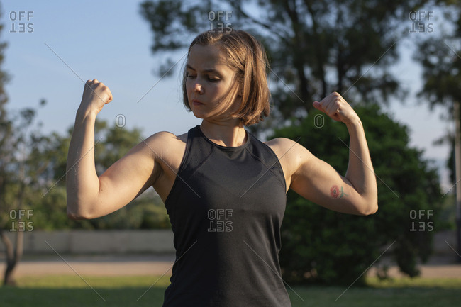Confident muscular woman flexing muscles while standing in park - Stock  Image - Everypixel