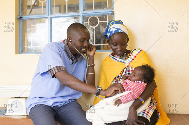 Pediatrician using stethoscope while examining baby held by mother at a clinic in Kenya