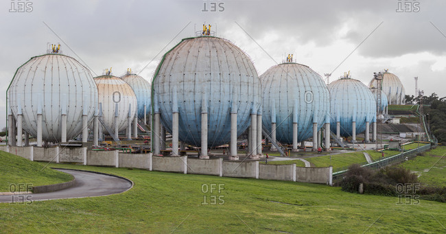Big sphere reservoirs placed in industrial area of Gijon in Spain and separated with fence on green grass