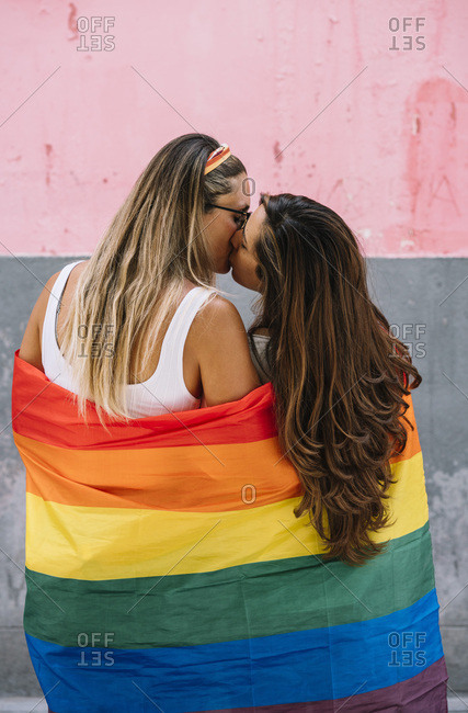 Couple lesbian woman with gay pride flag on the street of Madrid city