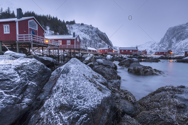 Typical fishermen houses called rorbu in the  snowy landscape at dusk Nusfjord Nordland County Lofoten Islands Norway Europe