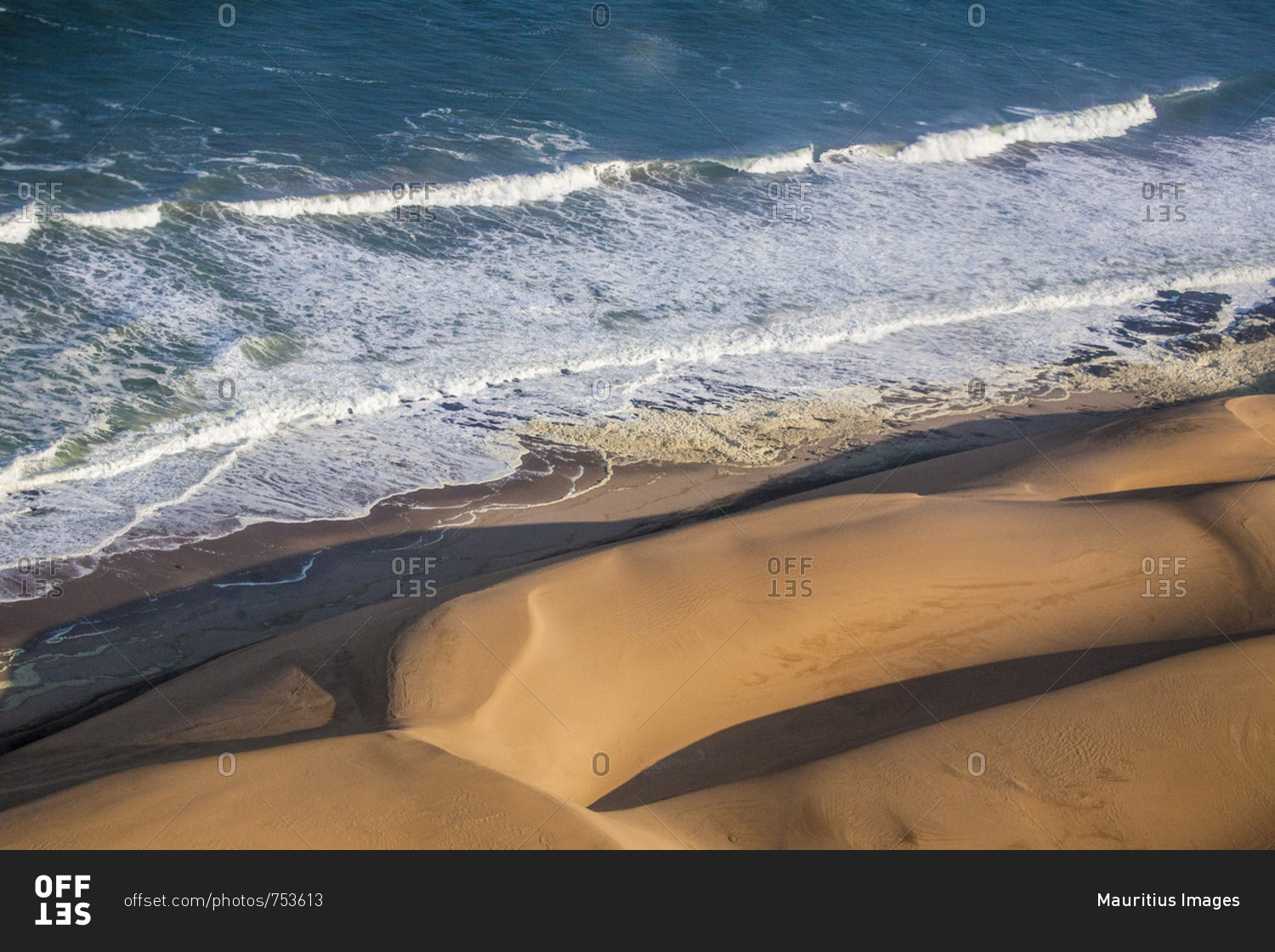 Aerial view of waves of the Atlantic Ocean crashing against the sandy dunes of the Namib desert Namibia Southern Africa